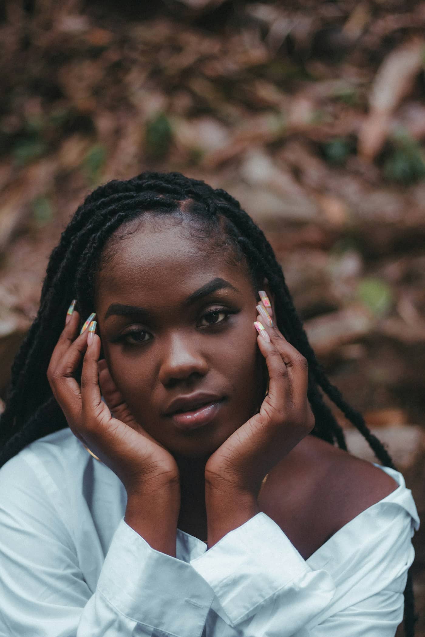Femme aux faux locks, les mains encadrant son visage